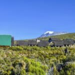 huts at Mount Kilimanjaro, the highest mountain in Africa (5892m), seen through the crops.