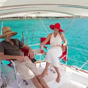 retired couple relaxing on a sailboat traveling through the Caribbean and enjoying tropical cocktails