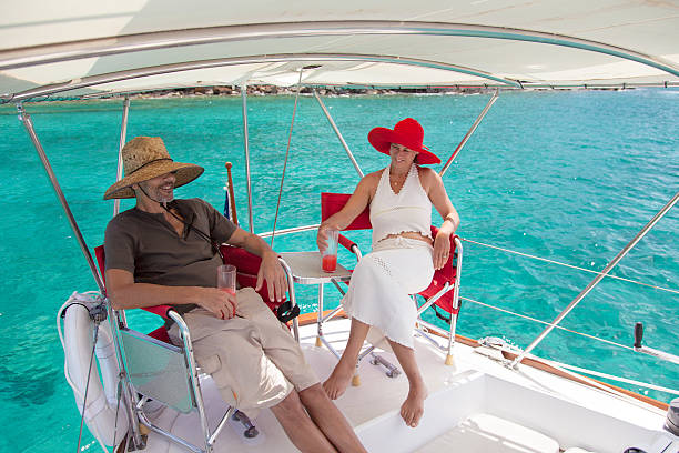 retired couple relaxing on a sailboat traveling through the Caribbean and enjoying tropical cocktails